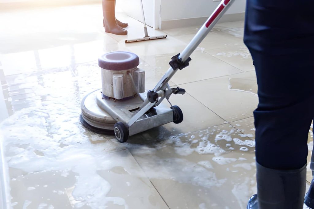 Tile cleaning Port Saint Lucie professionals using scrubbing machine and squeegee to clean tiled floor with soap and water