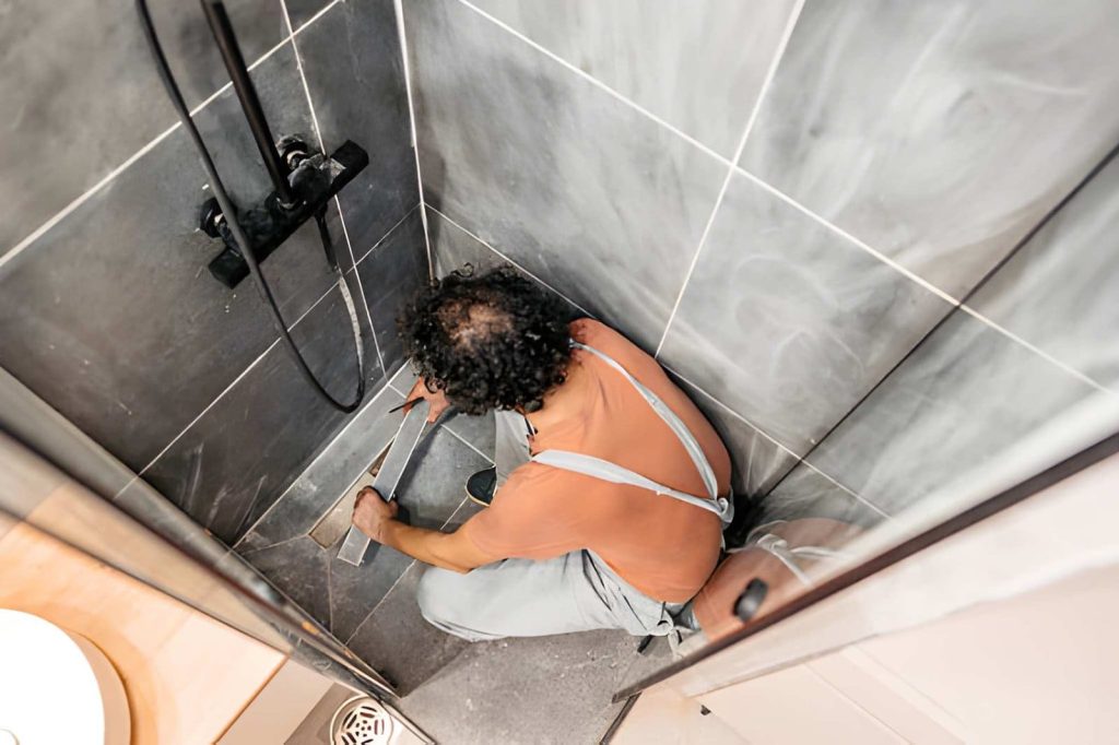 Leaking shower repair Melbourne technician measuring and marking tiles inside shower stall for precise repair work.